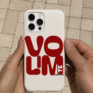 Könnte beinhalten: Eine weiße Smartphone-Hülle mit dem fetten roten Schriftzug "VO L'M" und dem kleineren schwarzen Text "SINCE 2012" auf der Rückseite. Die Hülle hat eine Aussparung für ein Dreifach-Kamerasystem und ist für ein rechteckiges Mobilgerät ausgelegt.
