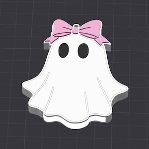 以下が含まれることがあります： ピンクのリボンと2つの黒い楕円形の目が付いた、白いお化けの形をした装飾品。お化けは灰色の輪郭で3D効果があり、背景は濃い灰色のグリッドです。