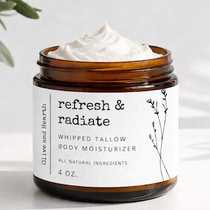 Puede incluir: Un tarro de vidrio marrón lleno de crema hidratante corporal batida blanca. El tarro tiene una etiqueta blanca con el texto "refresh & radiate" y "Whipped Tallow Body Moisturizer". El tarro contiene 118 ml de producto.