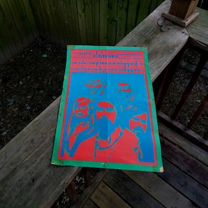 May include: A vintage concert poster with a psychedelic design featuring four faces in red and blue on a blue background. The poster has the text "The Grateful Dead" and "Winterland" in white.