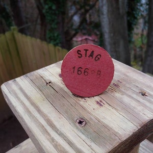 May include: A red wooden disc with the text "STAG 166°B" engraved on it.