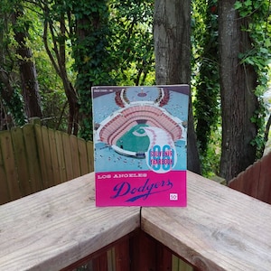 May include: A vintage 1950 Los Angeles Dodgers souvenir yearbook with a pink cover and a photo of a baseball stadium. The text "Los Angeles Dodgers" and "1950" are printed on the cover.