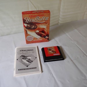 May include: A red, white, and black Sega Genesis game cartridge for Al Michaels's  Hardball III. The game cartridge is on a white surface next to a white instruction manual and a red, white, and black box with the same game title.