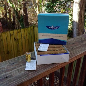 May include: A box of brass light bulb sockets labeled "Eagle Specification Grade Wiring Devices". The box is sitting on a wooden deck.