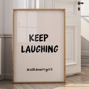 May include: A framed print with a light beige background and a wooden frame. The words "KEEP LAUGHING" are in bold black letters, with "Al still doesn't get it" below. The print is displayed near a white door.