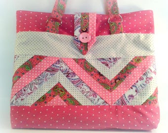 May include: A pink and white patchwork tote bag with a chevron pattern. The bag has a pink button and two fabric straps.