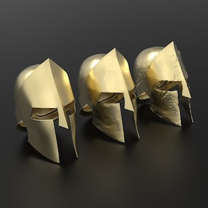 May include: Three gold-coloured Spartan helmets, each with a unique design, are arranged on a black surface. The helmets are made of metal and have a shiny finish.