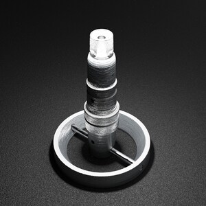 Peut inclure: Un objet en métal argenté avec une base ronde et un sommet cylindrique haut. Le sommet est composé de plusieurs anneaux empilés, et la base a une petite barre horizontale qui s'étend de celle-ci.