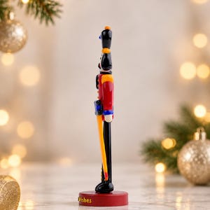 Close-up of the personalized 3D-printed base paired with the handmade glass Nutcracker, showing the raised yellow Christmas Wishes lettering.