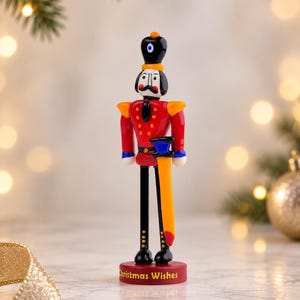 Holiday display of a handmade glass Nutcracker on a reflective tabletop, surrounded by soft golden lights and Christmas greenery.