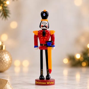 Detailed view of the Nutcracker's black crown-like hat with an orange glass ornament and white-and-blue central facial detail.