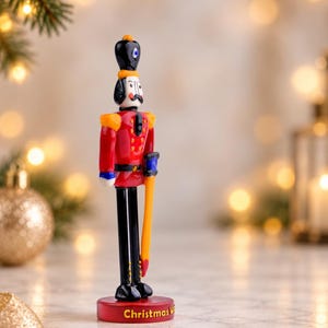 Three-quarter view of a colorful glass Nutcracker with glossy red, orange, blue, black, and white details and a traditional toy soldier design.