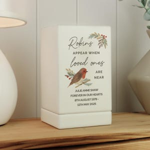 May include: White ceramic candle holder with a robin illustration and the text "Robins appear when loved ones are near". The text below the illustration reads "Julie Anne Shaw Forever in our hearts 8th August 1978- 11th May 2025".