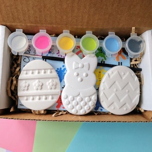 Puede incluir: Un conjunto de adornos de cerámica con temática de Pascua para pintar, que incluye un huevo, un conejito y otro huevo. El conjunto viene con seis pequeños botes de pintura de varios colores: blanco, rosa, amarillo, verde, azul y negro.