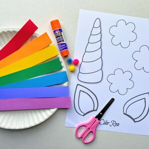 Items for the unicorn paper plate craft. One paper plate, seven colored strips of paper, glue, 3 pom poms, scissors and a cardstock age with a unicorn horn, two ears and three flower shapes to color and cut out.