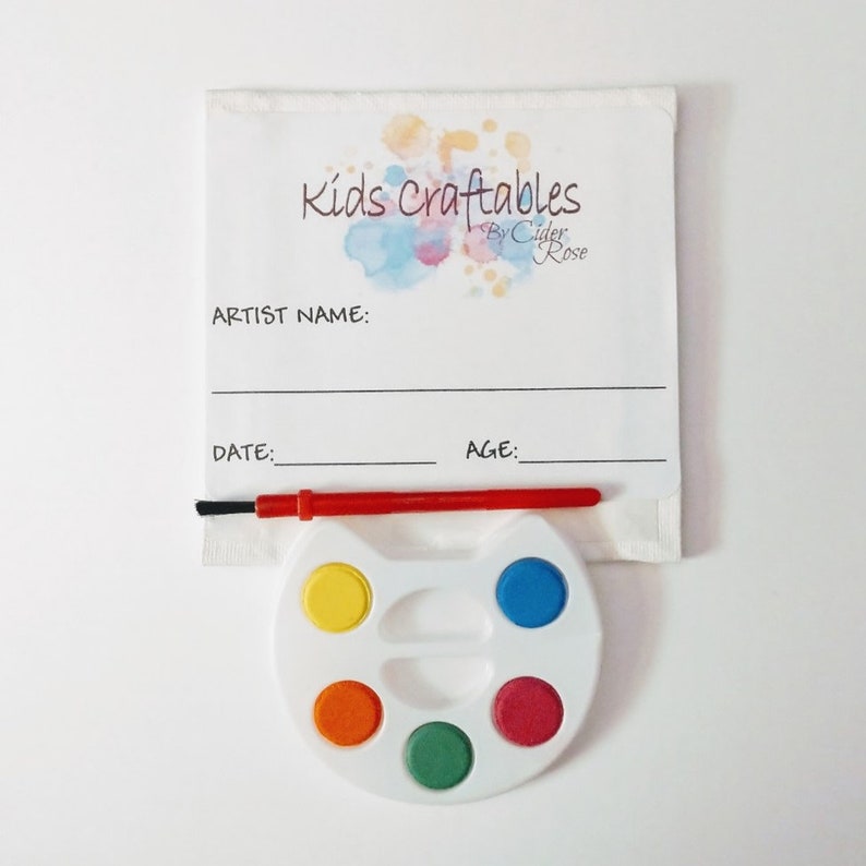 K&ouml;nnte beinhalten: Eine wei&szlig;e Farbpalette mit sechs Farbt&ouml;pfen, einem roten Pinsel und einem wei&szlig;en Papier mit dem Text "Kids Craftables by Cider Rose" und Platz f&uuml;r den Namen des K&uuml;nstlers, das Datum und das Alter.