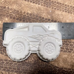 3.8 inch plaster monster truck magnet with flames on the side.