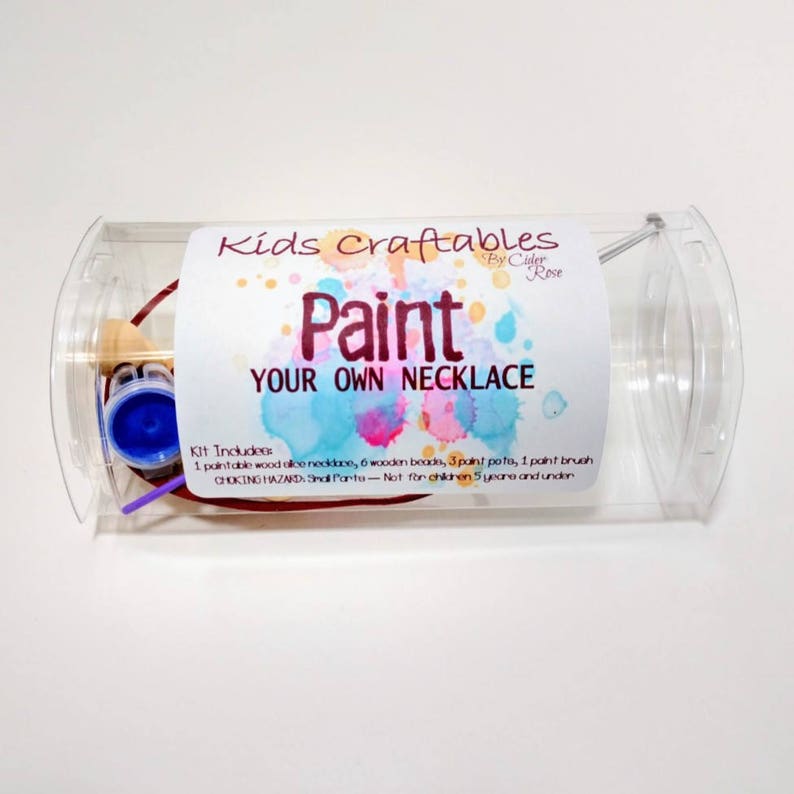 May include: A clear plastic tube containing a paint your own necklace craft kit. The kit includes a wooden necklace, wooden beads, paint pots, and a paint brush. The label reads "Kids Craftables Paint Your Own Necklace".
