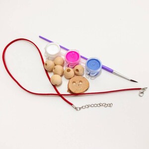 May include: A DIY necklace kit with wooden beads, red cord, a silver chain, and three small paint pots in white, pink, and blue.