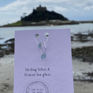 May include: Sterling silver hoop earrings with a light blue sea glass charm. The earrings are displayed on a white card with the text "Sterling Silver & Cornish Sea glass" and a logo that says "Pebble Love Cornwall, Cornish Sea glass Silver Jewellery, Handmade by Terrie".