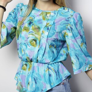 May include: A blue, green, and purple floral print blouse with a gathered waist and 3/4 sleeves.