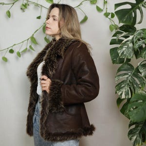 Pode incluir: Casaco castanho em pele sint&eacute;tica com gola e punhos em p&ecirc;lo sint&eacute;tico. O casaco tem um design cl&aacute;ssico com fecho de bot&atilde;o e bolsos. A guarni&ccedil;&atilde;o de p&ecirc;lo adiciona um toque de luxo. Um casaco elegante e quente para os meses frios.