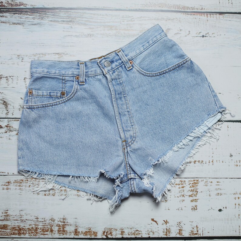 Puede incluir: Pantalones cortos de mezclilla azul claro con bordes deshilachados. Los pantalones cortos tienen cintura alta y un dise&ntilde;o cl&aacute;sico de cinco bolsillos.