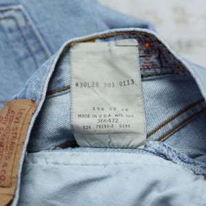 Puede incluir: Vaqueros de mezclilla azul claro con un parche de cuero marr&oacute;n y una etiqueta blanca con el texto "Levi Strauss & Co. Quality Clothing" y "W30L28 901 0113 156 CS 20 MADE IN U.S.A. WPL 123 366472 524 79191-3 0193".