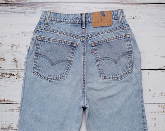 May include: Light blue denim jeans with a classic five-pocket design. The back of the jeans features two pockets with the Levi's signature arcuate stitching, a small red tab, and a brown leather patch.