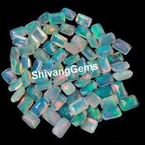 Puede incluir: Un montón de piedras preciosas de ópalo blanco en talla esmeralda rectangular. Los ópalos tienen un brillo iridiscente azul claro y verde.