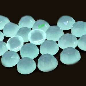 May include: A group of 18 light blue cabochon gemstones, each with a faceted, rounded shape. The gemstones are arranged in a loose pile, with some overlapping.