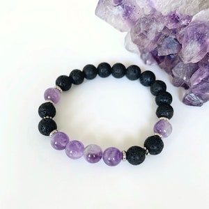May include: A black lava rock and amethyst beaded bracelet. The bracelet features a mix of black lava rock beads and purple amethyst beads.