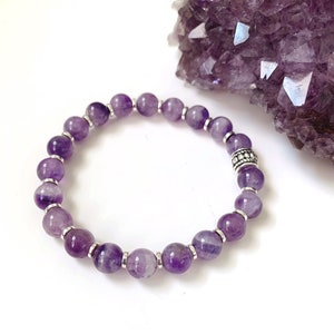 Pu&ograve; includere: Un braccialetto in ametista viola con perline d'argento. Il braccialetto &egrave; realizzato con perline rotonde e ha un ciondolo d'argento.