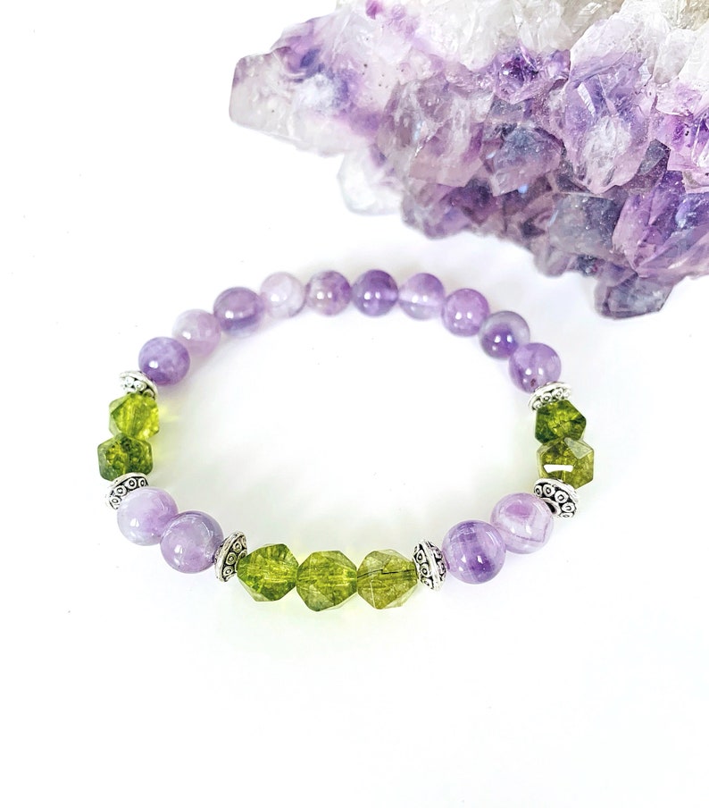 May include: A purple and green gemstone bracelet with silver accents. The bracelet is made with round and faceted beads.