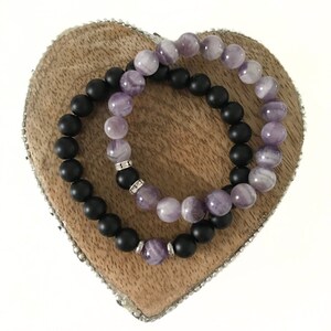 May include: Two bracelets, one with black matte beads and the other with purple and white amethyst beads.