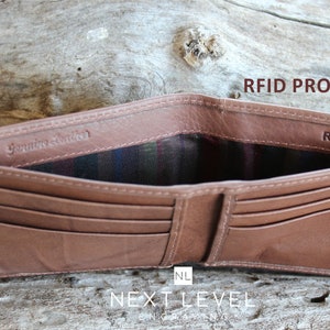 May include: A brown leather wallet with multiple card slots and a billfold. The wallet is open to reveal a plaid lining and the text "Genuine Leather" and "RFID" printed on the inside. The text "RFID Protection" is printed on the top right corner of the image.