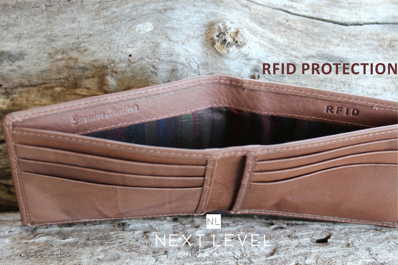 May include: A brown leather wallet with multiple card slots and a billfold. The wallet is open to reveal a plaid lining and the text "Genuine Leather" and "RFID" printed on the inside. The text "RFID Protection" is printed on the top right corner of the image.