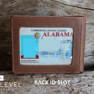May include: A brown leather wallet with a clear plastic window for displaying an ID card. The window shows a commercial driver's license from Alabama. The text on the license reads "COMMERCIAL DRIVER LICENSE ALABAMA CLASS BMV EXP 07-31-20 Secretary Stan Stabler Secretary of Law Enforcement 302 05-28-2016 5-08 WT 160". The wallet has a back ID slot.