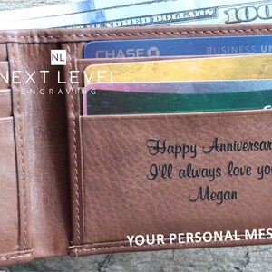 May include: A brown leather wallet with a personalized message that reads "Happy Anniversary I'll always love you Megan". The wallet has a card slot and a billfold. The wallet is open and there are credit cards inside.