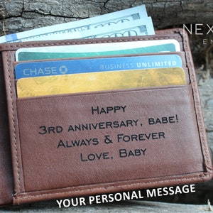 May include: A brown leather wallet with a personalized message that reads "Happy 3rd Anniversary, Babe! Always & Forever Love, Baby". The wallet has a credit card slot and a money clip.