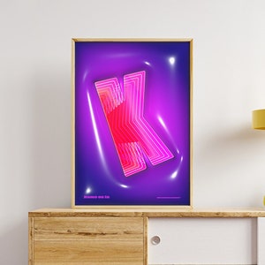 Op de afbeelding: Een ingelijste poster met een neon roze en rode letter K op een paarse achtergrond. De tekst "Home on In" staat onderaan de poster.