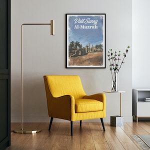 May include: A yellow armchair with black legs sits in a room with a poster that reads "Visit Sunny Al-Mazrah" and a vase with pink flowers on a side table.