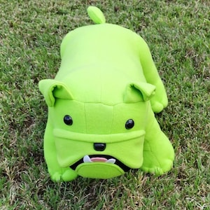 May include: A bright lime green plush bulldog toy featuring smooth fabric construction, two round black plastic eyes, a small black nose, and an open mouth displaying two white teeth and a small pink tongue, with a small upright tail.