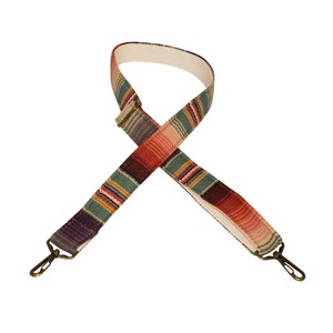 May include: A colorful striped fabric strap with brass hardware. The strap is woven with red, pink, green, and purple stripes.