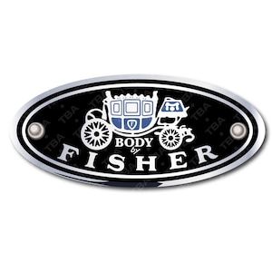 Op de afbeelding: Een ovaal, zwart en zilverkleurig embleem met de witte tekst "BODY by FISHER". Een wit koetsontwerp met blauwe accenten is gecentreerd boven de tekst. Aan weerszijden van het embleem bevinden zich zilveren klinknagels.