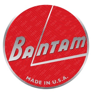 Puede incluir: Un logotipo circular rojo y plateado con la palabra "BANTAM" en una fuente plateada estilizada. El logotipo tiene un fondo rojo con círculos concéntricos y un triángulo plateado. El texto "MADE IN U.S.A." está en la parte inferior del logotipo.
