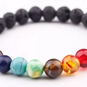 May include: A black lava rock bracelet with seven colorful gemstone beads. The beads are purple, blue, turquoise, green, brown, amber, and red.