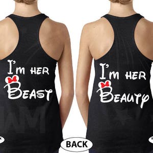 May include: Two black racerback tank tops with white text that reads "I'm her Beast" and "I'm her Beauty". Each tank top has a red bow on the text.