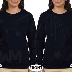 May include: A navy blue long-sleeved sweatshirt with a black and white design of shooting stars and stars. The sweatshirt has the word "SWIM" printed on the front.
