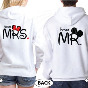 May include: White hooded sweatshirts with the text "Future Mrs." and "Future Mr." in black with a Mickey Mouse head silhouette. The "Mrs." has a red bow and the "Mr." has black ears.